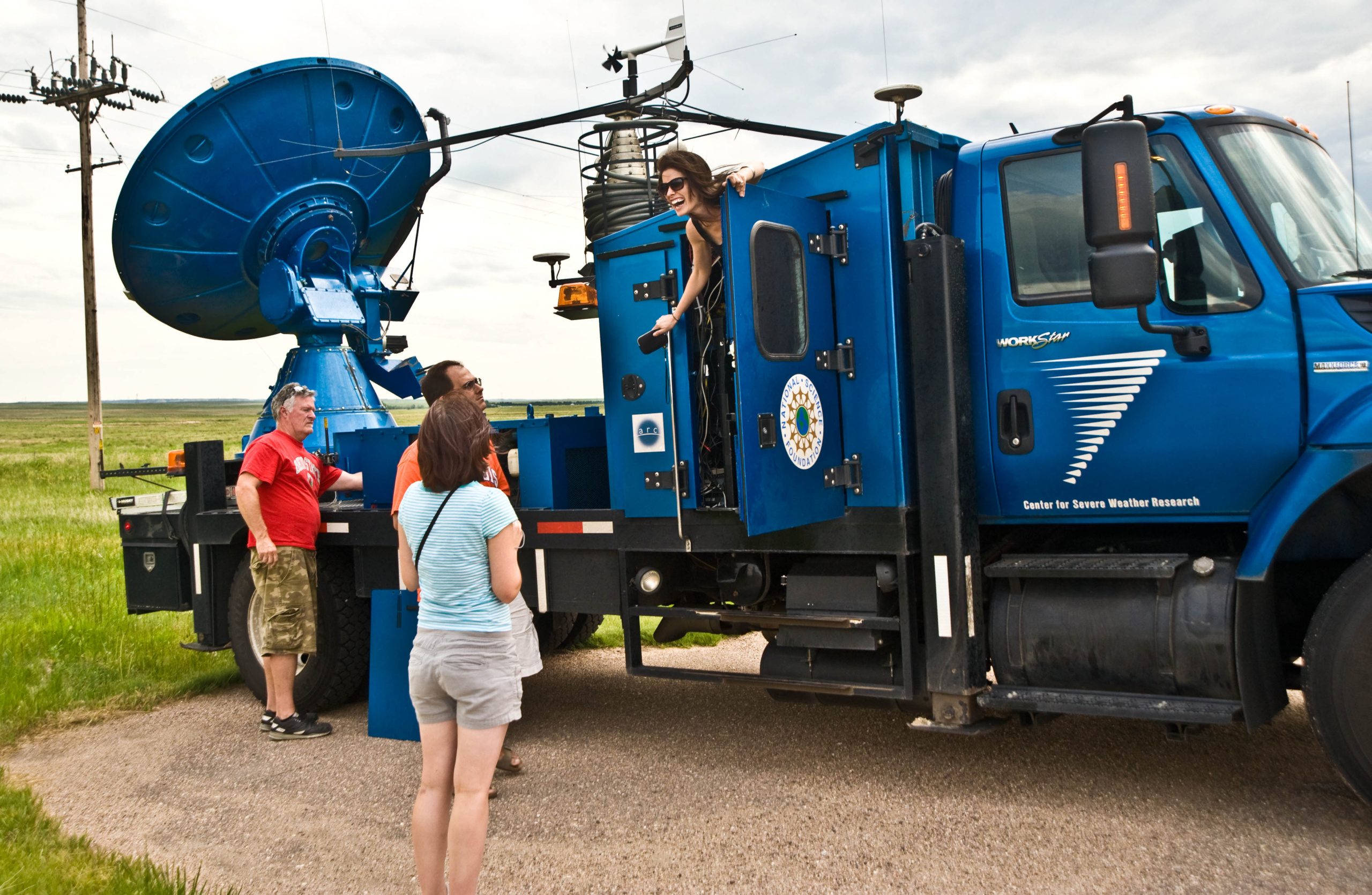 Karen Kosiba leans out of mobile mesonet vehicle with a C-band on wheels (COW) radar to speak to other researchers. (Courtesy photo/Karen Kosiba)